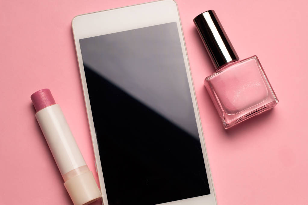 το top view βερνίκια νυχιών, κραγιόν και κινητό τηλέφωνο Ροζ παστέλ φόντο - Φωτογραφία, εικόνα