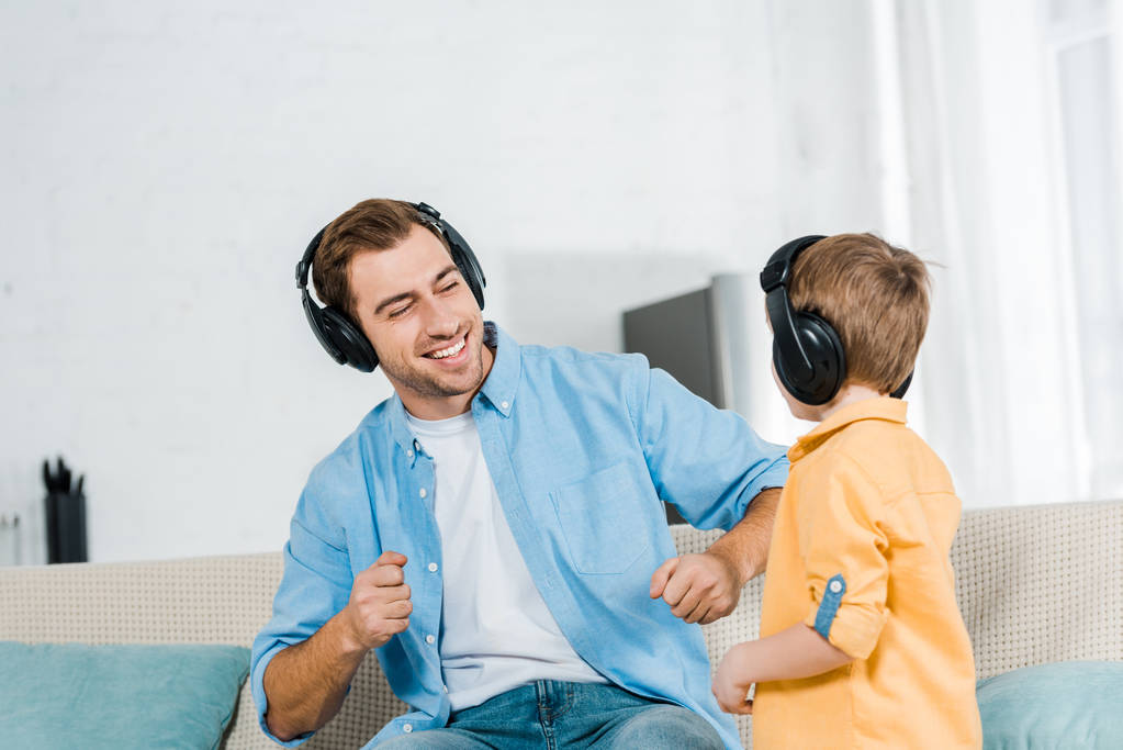 自宅で音楽を聴くヘッドフォンで未就学児の息子と幸せな父  - 写真・画像
