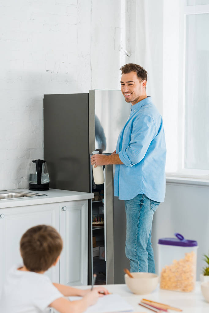 szelektív összpontosít az óvodás fia rajz reggeli közben konyhában, előtérben a mosolygó Atya - Fotó, kép