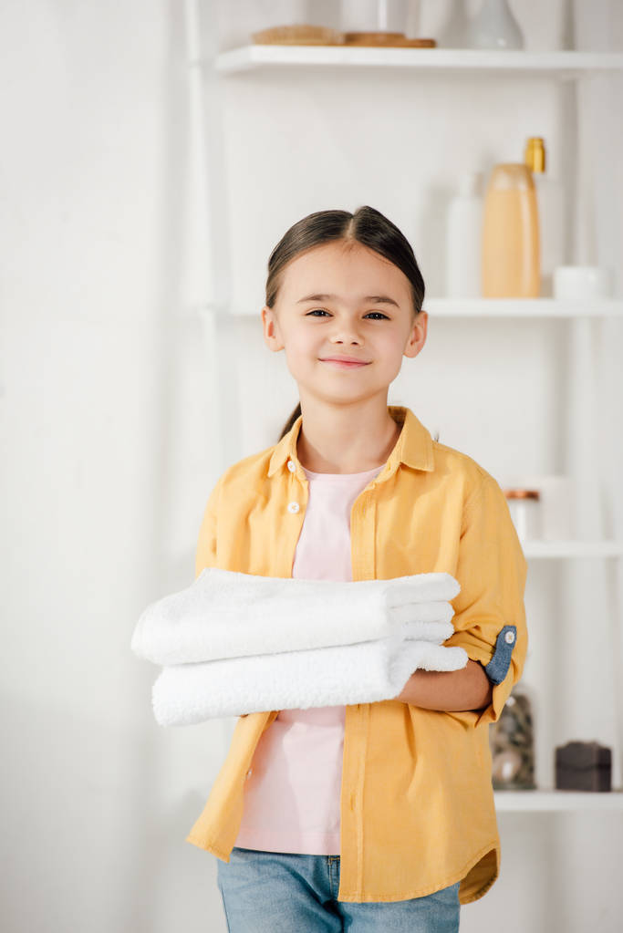 Selektiver Fokus des Kindes im gelben Hemd, das Handtücher zu Hause hält - Foto, Bild