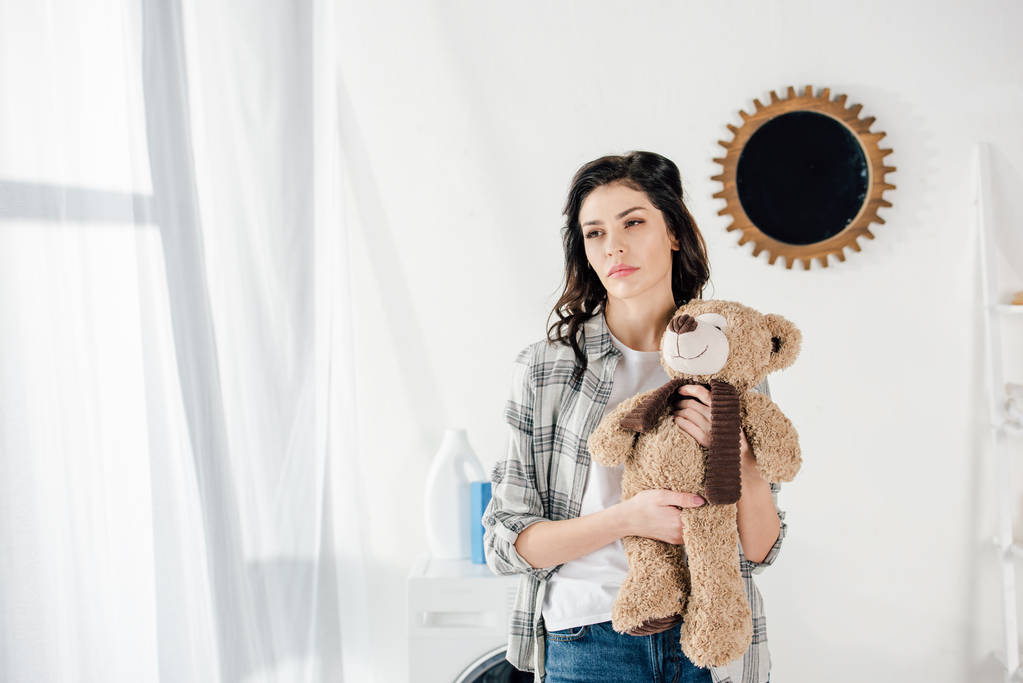 Женщина держит медвежью игрушку и думает дома
 - Фото, изображение