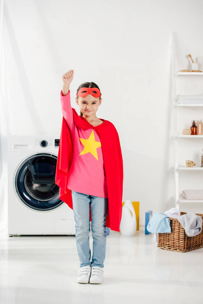 Kind im roten hausgemachten Superheldenanzug in der Waschküche - Foto, Bild
