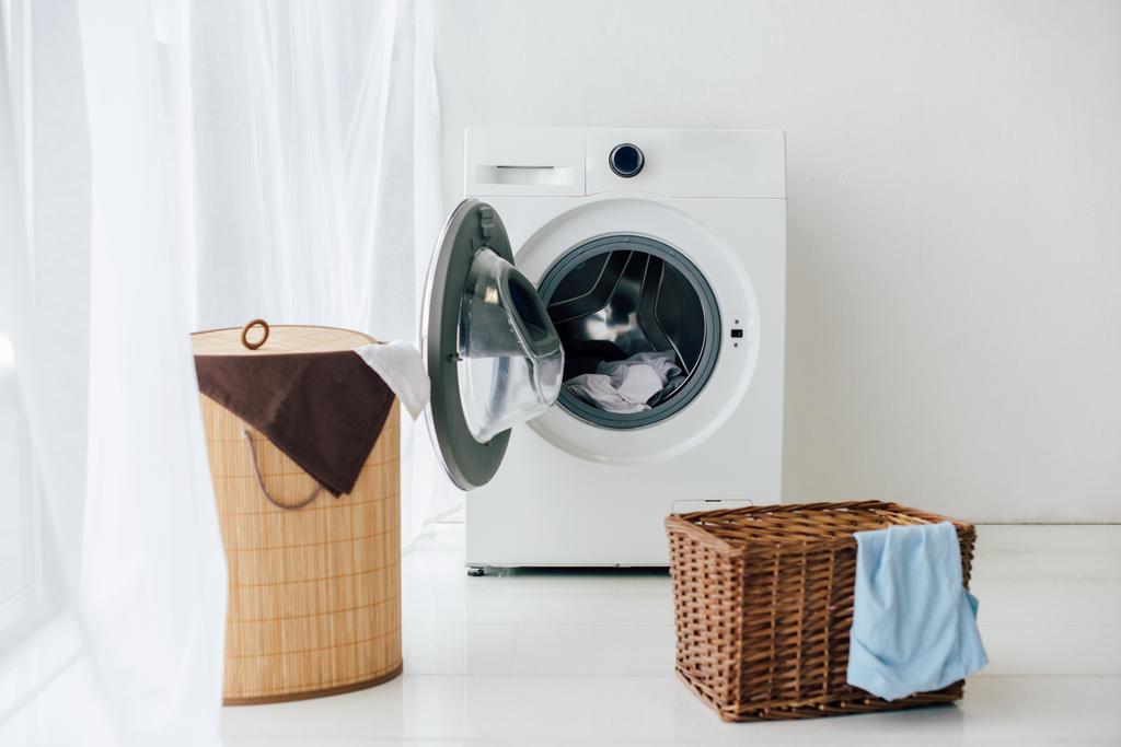 lavadora abierta y cestas marrones en lavadero
 - Foto, imagen