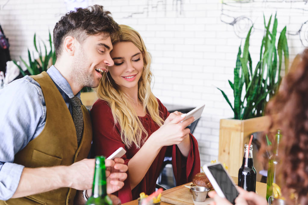 вибірковий фокус красивої пари посміхається і використовує цифрові пристрої в кафе
  - Фото, зображення