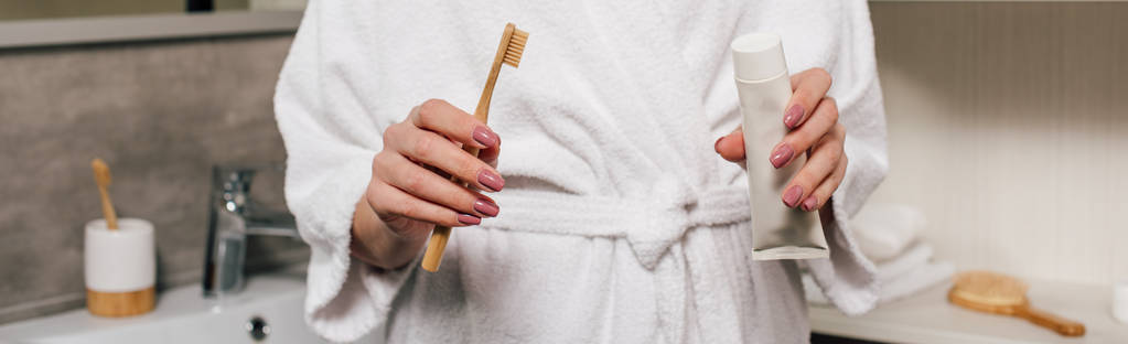 colpo panoramico di donna che tiene dentifricio e spazzolino in bagno
 - Foto, immagini