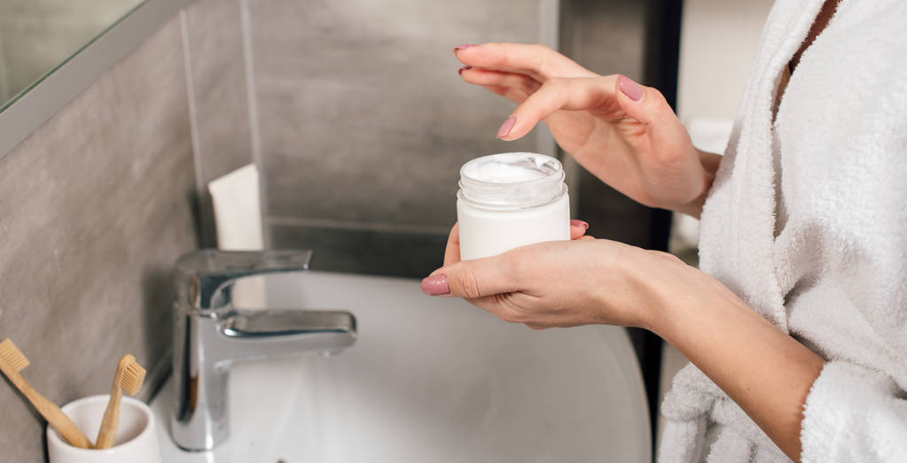 plan panoramique de femme tenant conteneur avec lotion dans la salle de bain
 - Photo, image