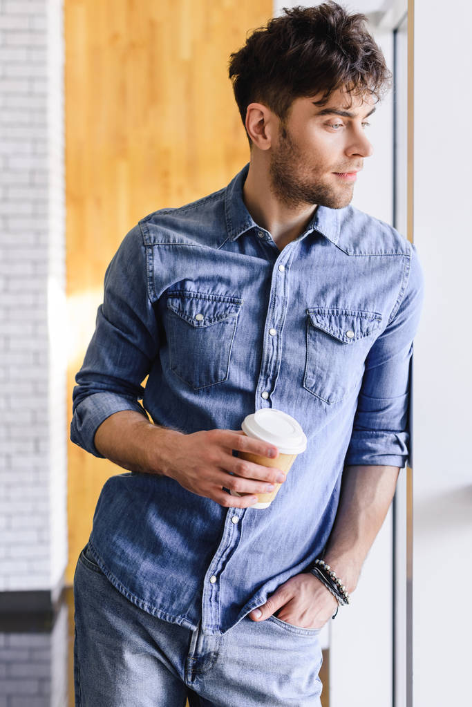 homem bonito de pé e segurando copo de papel no café
  - Foto, Imagem