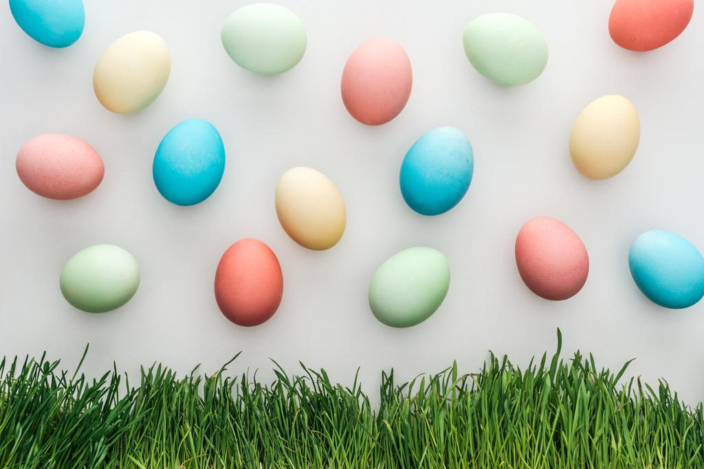 vista superior de ovos de páscoa pastel pintados isolados em cinza com grama
 - Foto, Imagem