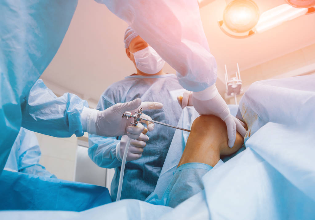 アースコープ手術。現代の関節鏡検査ツールと手術室でのチームワークで整形外科医。膝の手術だ。病院の背景 - 写真・画像