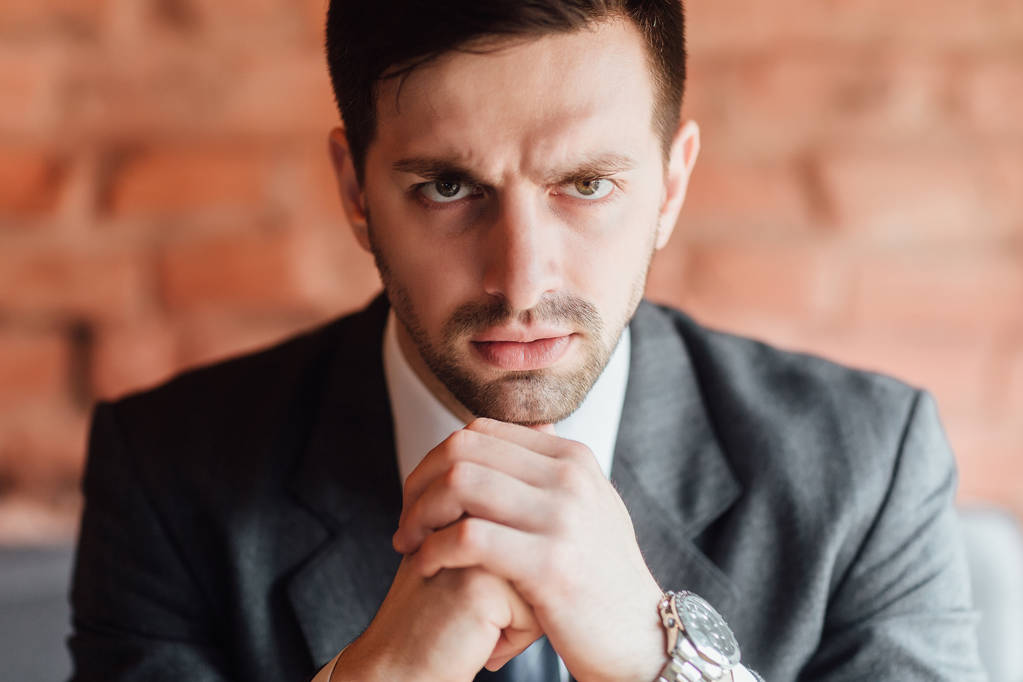 Portrait of young businessman with serious face and hands folded together  - Photo, Image