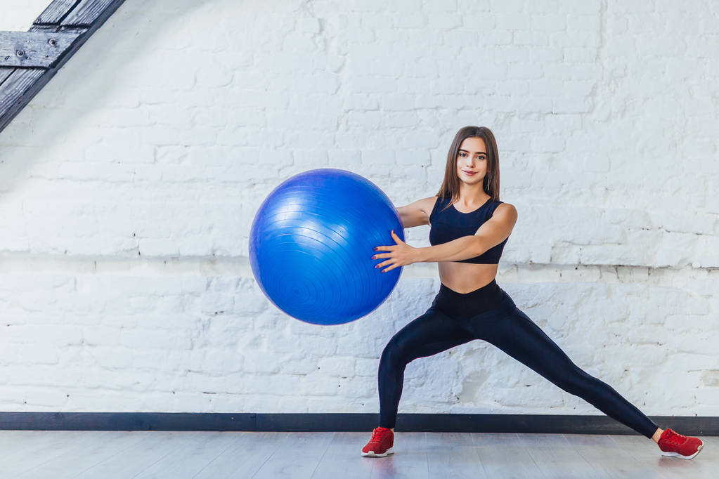  Junge Frau trainiert mit Fitnessball im Fitnessstudio  - Foto, Bild