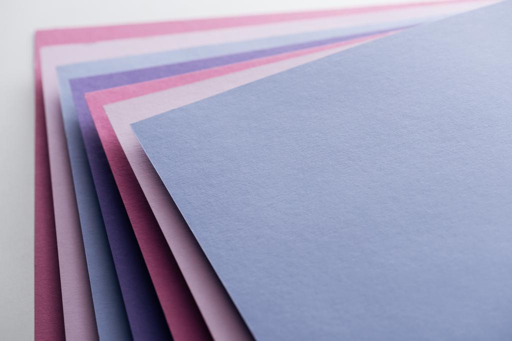 άδειο μπλε, λευκό, ροζ και μοβ φύλλα χαρτιού σε λευκό φόντο  - Φωτογραφία, εικόνα