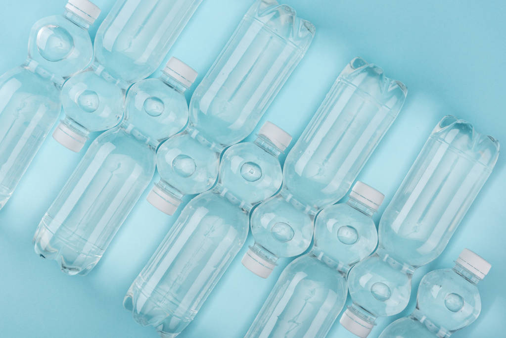 vista superior de botellas de agua de plástico arregladas sobre fondo turquesa
 - Foto, Imagen