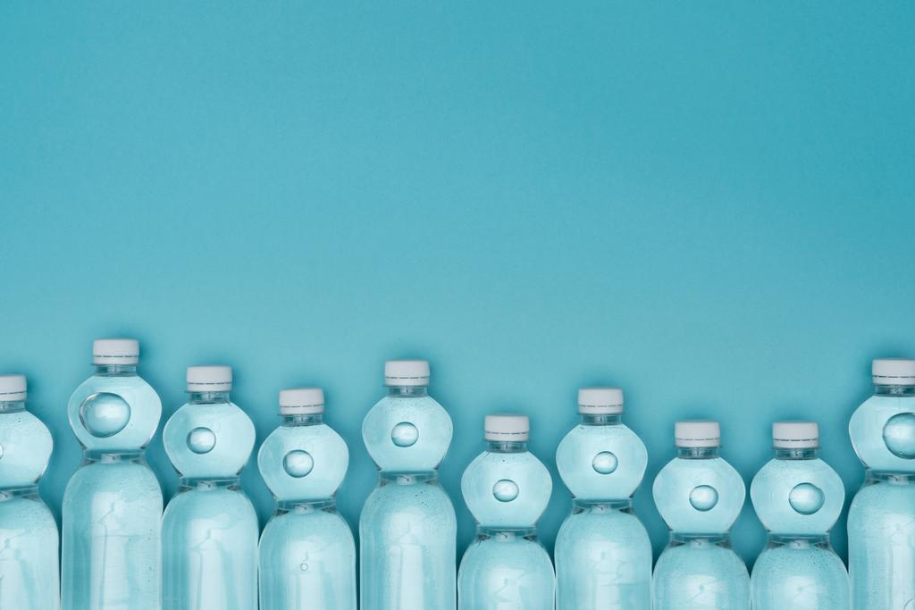 вид пластиковых бутылок с водой, изолированных на бирюзовом фоне с копировальным пространством
 - Фото, изображение