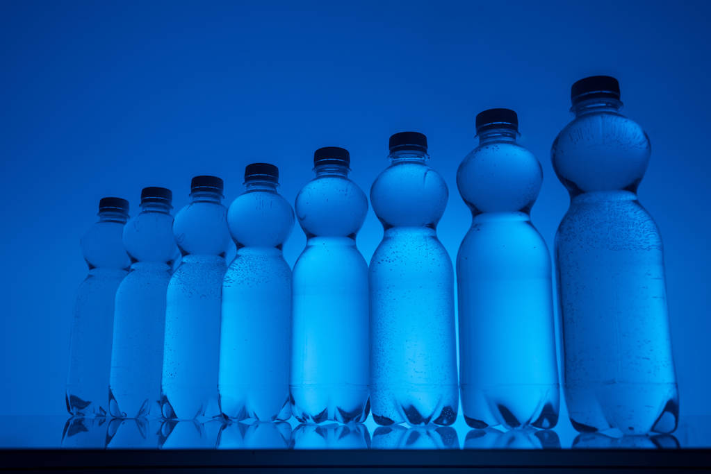 neon mavi zemin üzerine şeffaf su şişeleri - Fotoğraf, Görsel