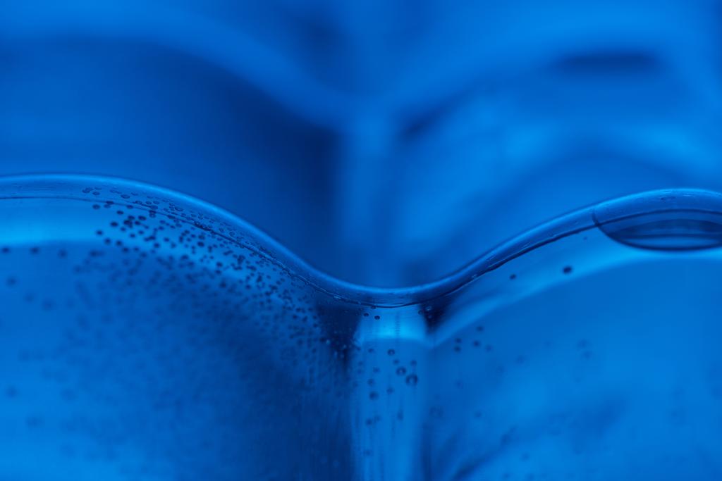 κοντινό πλάνο πλαστικό μπουκάλι νερού με τις φυσαλίδες και να αντιγράψετε χώρο σε μπλε φόντο  - Φωτογραφία, εικόνα