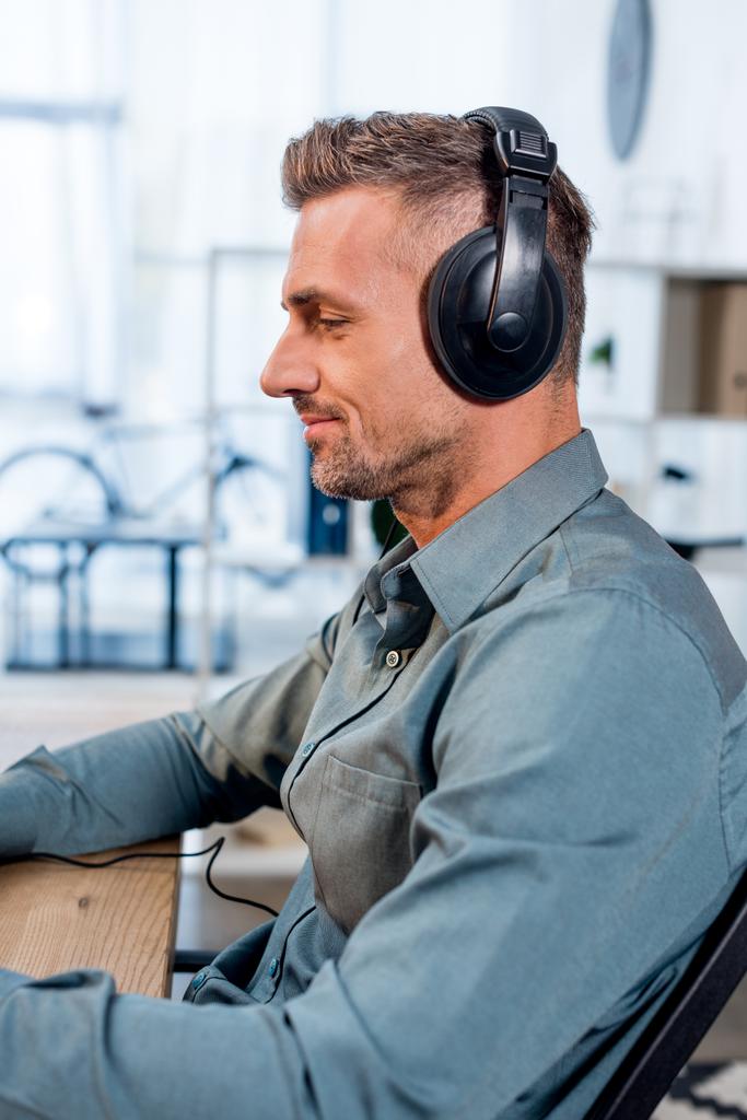 handsome cheerful man listening music in headphones in office - Photo, Image