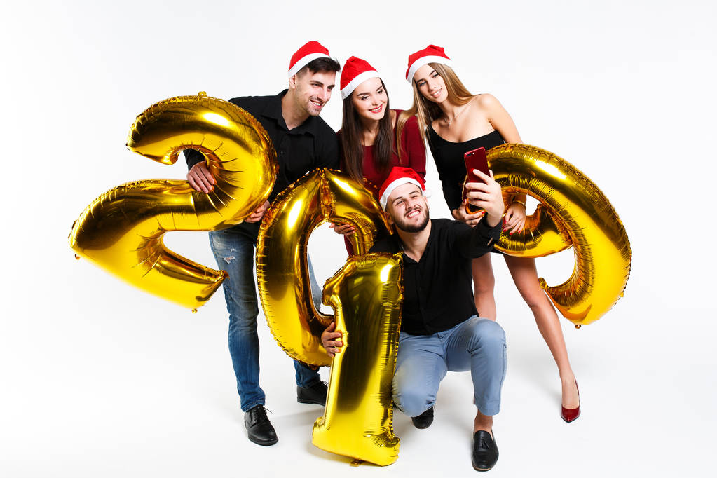 Retrato de grupo de amigos celebrando Año Nuevo, de pie con globos con números dorados en 2019 aislados sobre fondo blanco
 - Foto, imagen