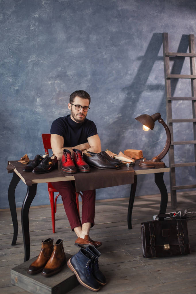 attractive shoemaker sitting at the table with repaired shoes - Photo, Image