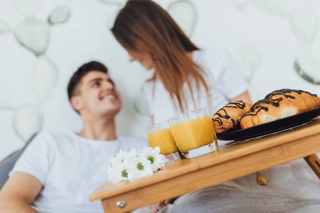 Young beautiful couple having breakfast in morning on bed, selective focus - Photo, Image