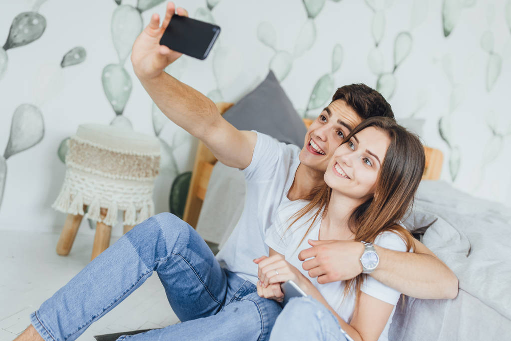 Nuori söpö pari tekee selfie kotona lähellä sänkyä
 - Valokuva, kuva