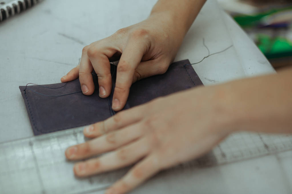 手作り革職人クラフト財布天然皮革の部分を使用して彼の仕事の場所を作るツールは、彼の手の写真をクローズ アップ - 写真・画像