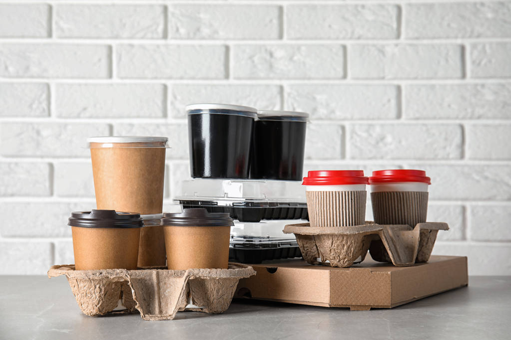 Verschillende takeout containers op tafel tegen witte bakstenen muur. Levering foodservice - Foto, afbeelding