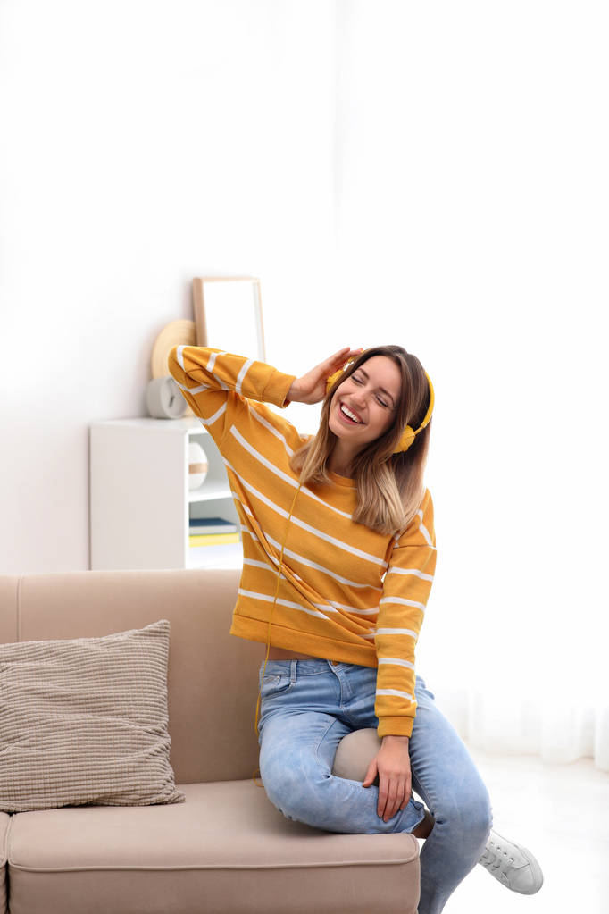 Fiatal nő élvezi a zenét otthon a kanapén fejhallgató - Fotó, kép