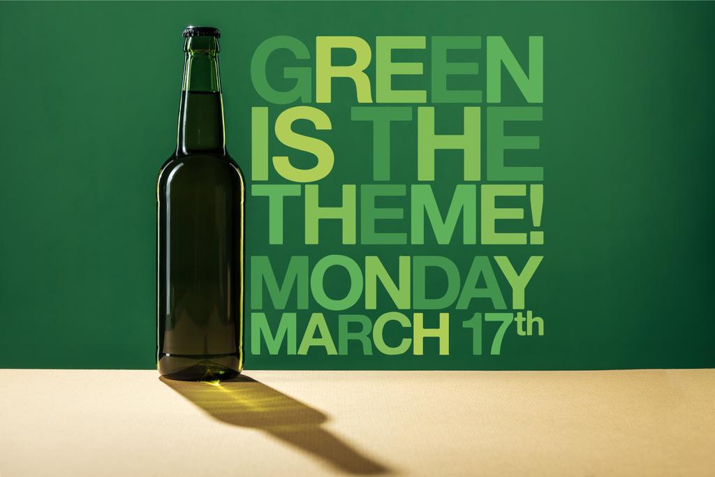 glass beer bottle near green is the theme lettering on green background - Photo, Image