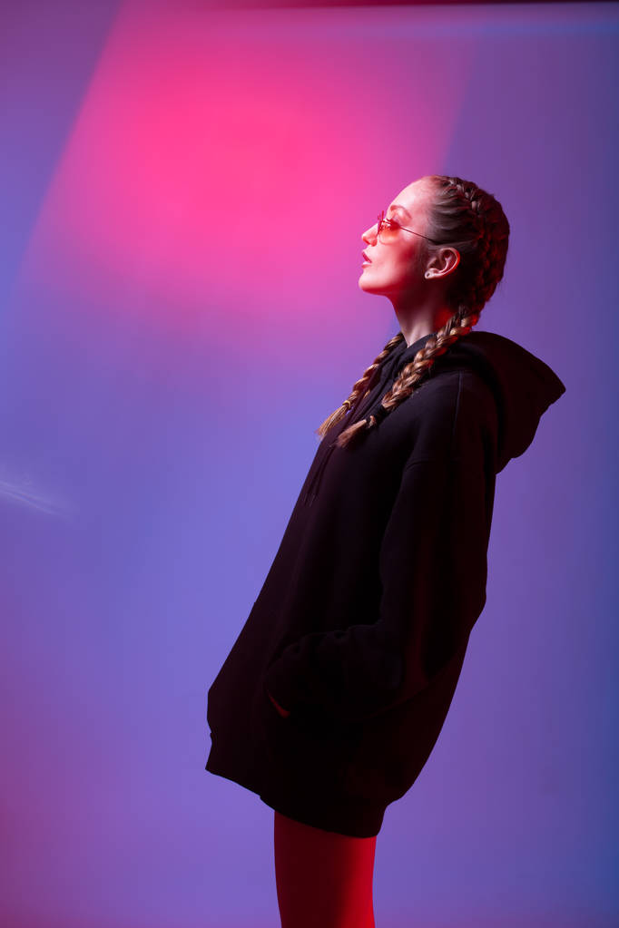 Siyah kazaklı kukuIeta ve güneş gözlüğü moda kız portresi yuvarlak şekil neon Işık Studio - Fotoğraf, Görsel