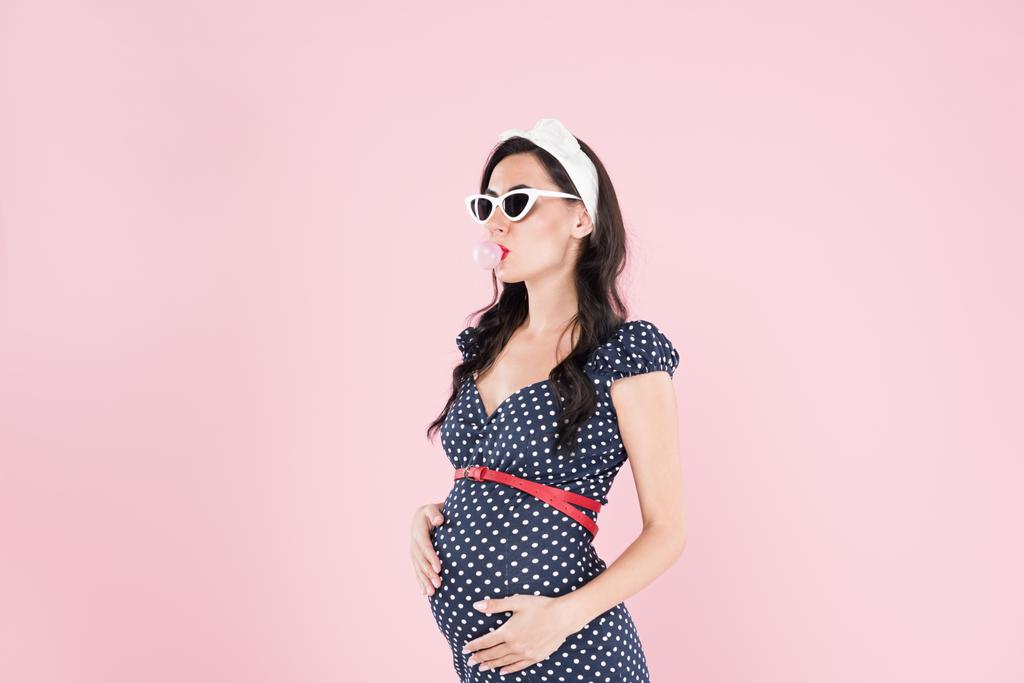 Pregnant woman in sunglasses chewing bubble gum isolated on pink - Photo, Image
