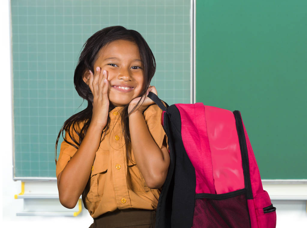 güzel mutlu ve heyecanlı kadın çocuk öğrenci taşıyan okul üniformalı çanta arkada okul ve eğitim çocuk için sınıf blackboard, gülümseyen neşeli ayakta - Fotoğraf, Görsel