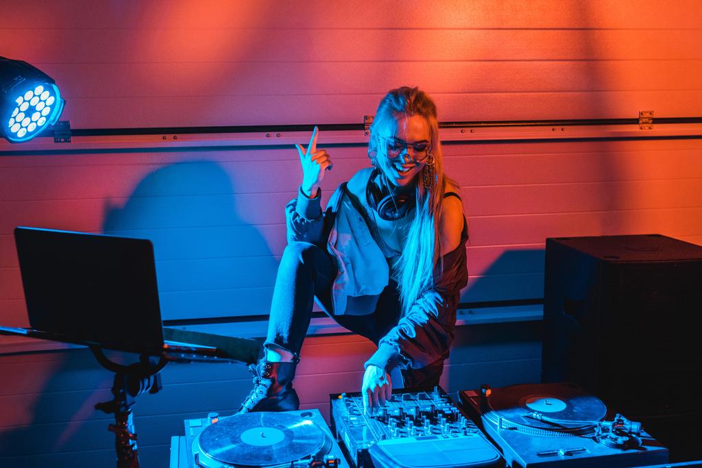 mulher dj elegante alegre em óculos gesticulando ao tocar dj mixer
  - Foto, Imagem