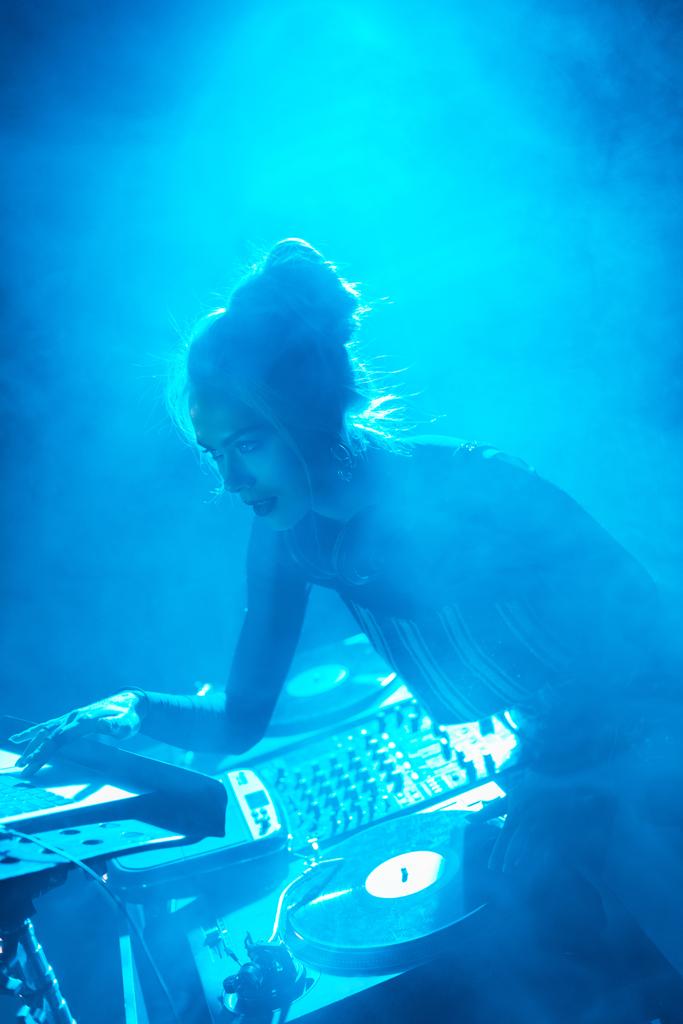 Sarı saçlı ayakta dumanlı gece kulübünde dj ekipmanları yakınındaki kadınla odaklı dj   - Fotoğraf, Görsel