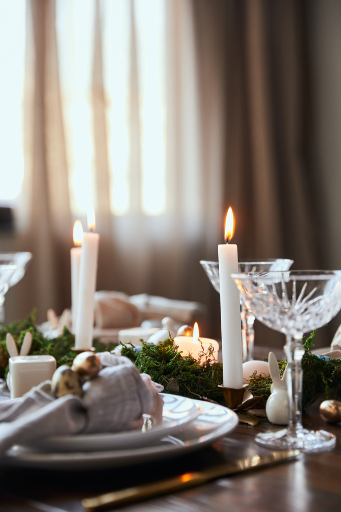 foco selectivo de velas ardientes cerca de platos, musgo y vasos de cristal en la mesa de madera en casa
 - Foto, Imagen