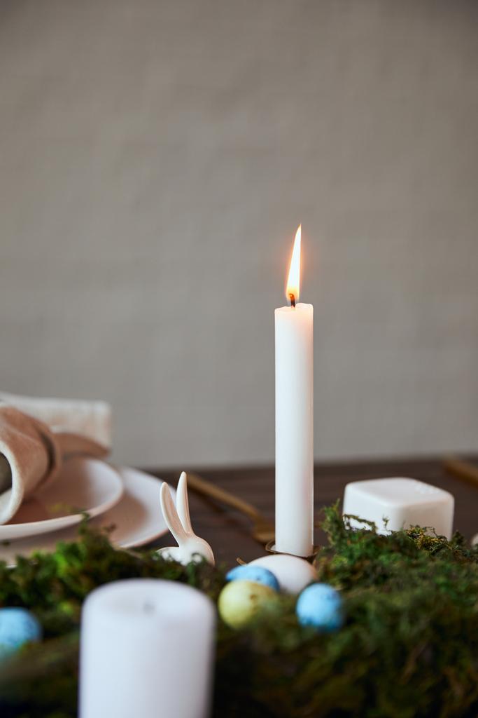Selektivní fokus hořící svíčku a desky v blízkosti mechu na dřevěný stůl doma - Fotografie, Obrázek