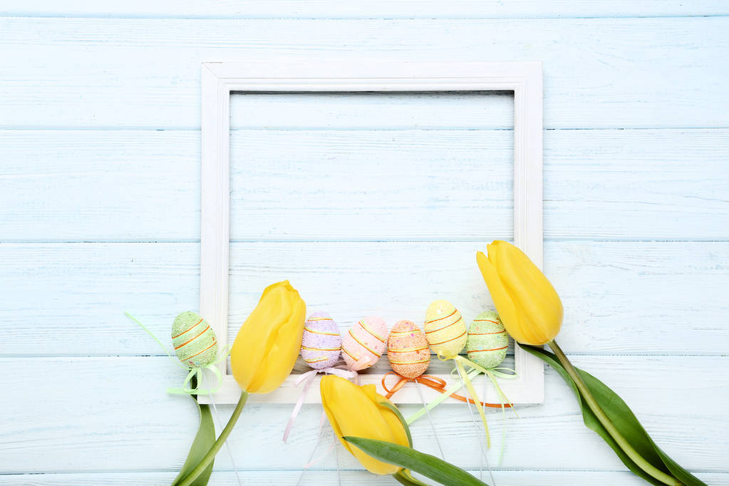 Žluté tulipány s velikonoční vajíčka a rámečku na dřevěný stůl - Fotografie, Obrázek