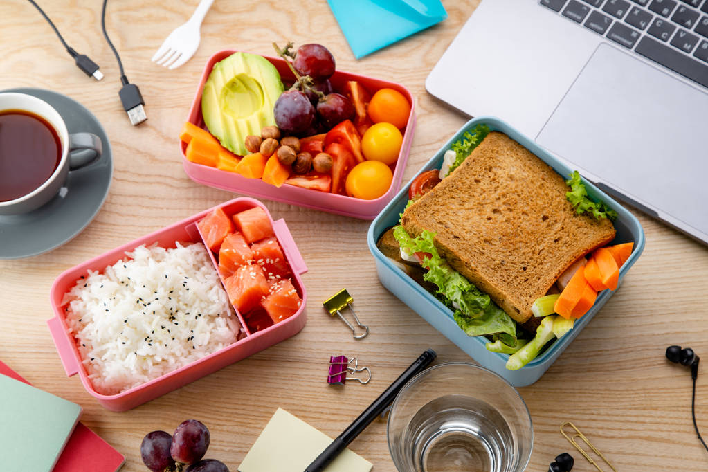  gezonde lunchgerechten in bento dozen in de buurt van laptop op houten tafel, officie lunch concept - Foto, afbeelding
