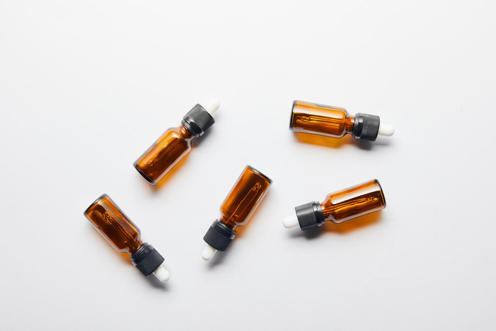 Top view of brown bottles with essential oil lying on grey surface - Photo, Image