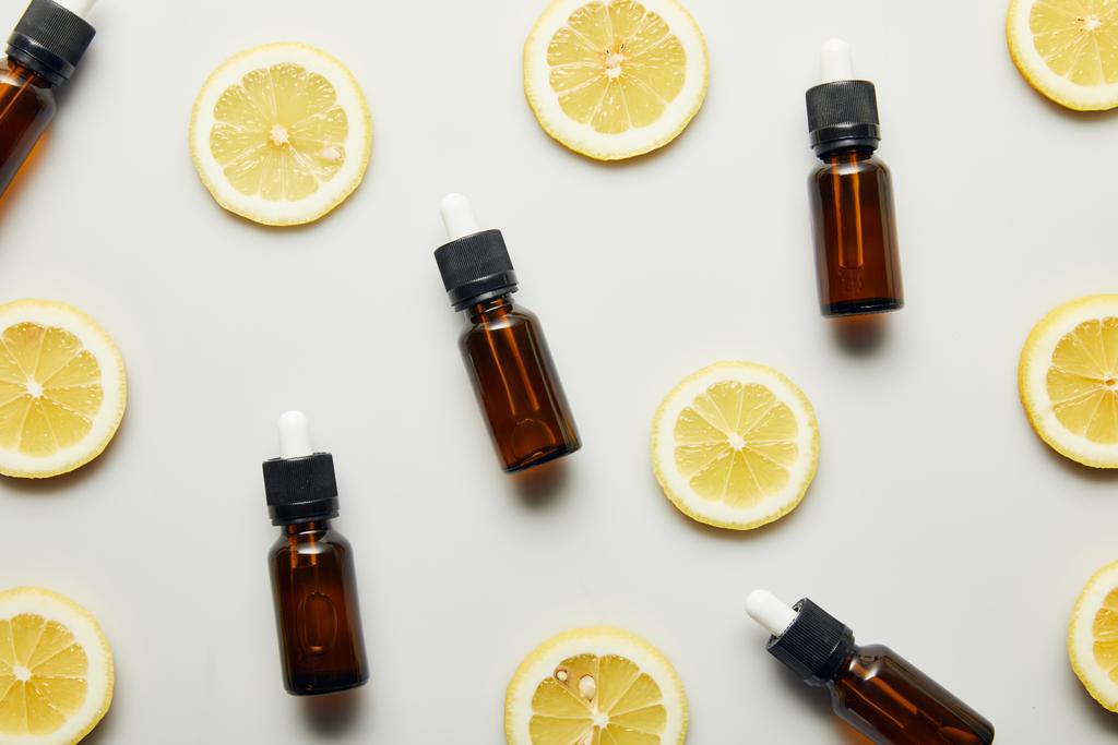 Flat lay com óleo essencial em garrafas e fatias de limão sobre fundo cinza
 - Foto, Imagem