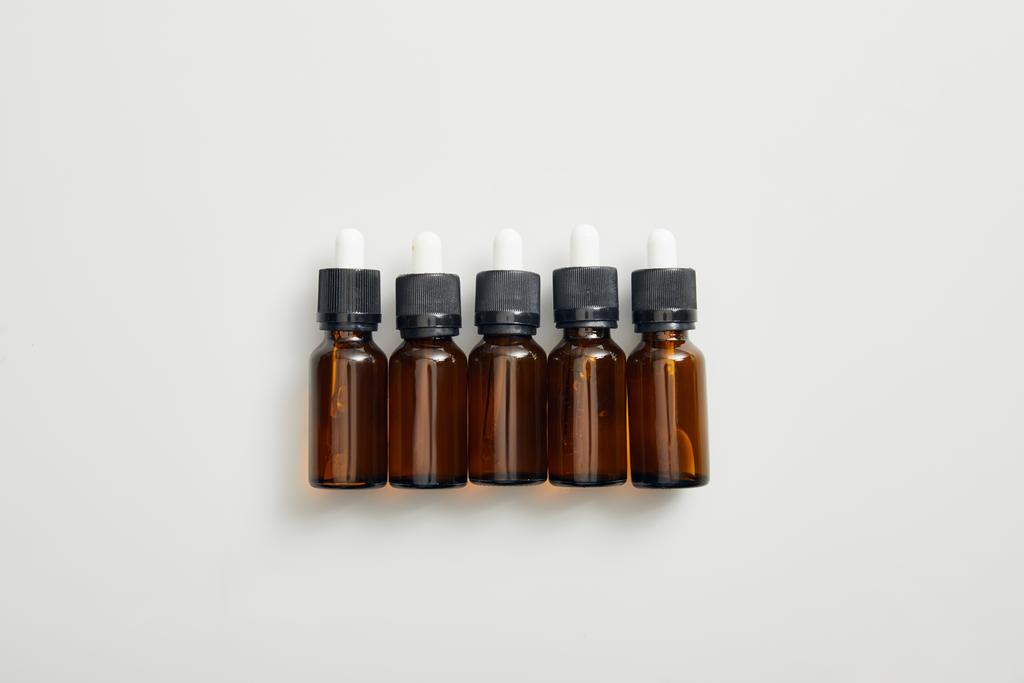 Vista superior de garrafas castanhas com óleo essencial sobre fundo cinzento
 - Foto, Imagem
