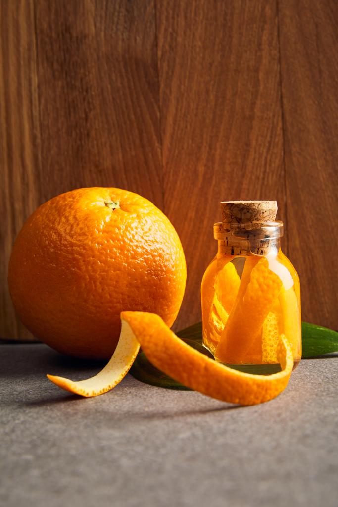 reife Orange und ätherisches Öl in Glasflasche auf Holzgrund - Foto, Bild