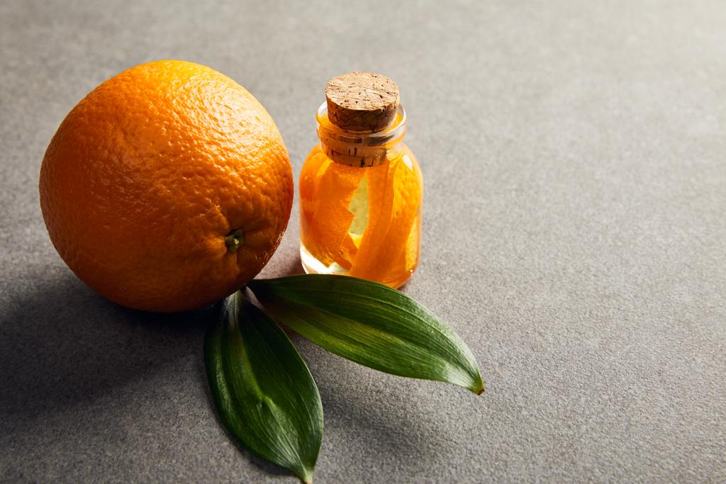 Φρέσκο ολόκληρο πορτοκάλι με αιθέριο έλαιο στην σκοτεινή επιφάνεια - Φωτογραφία, εικόνα