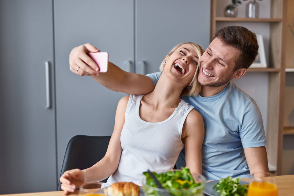 Pareja juguetona tomando selfie durante la comida
  - Foto, imagen
