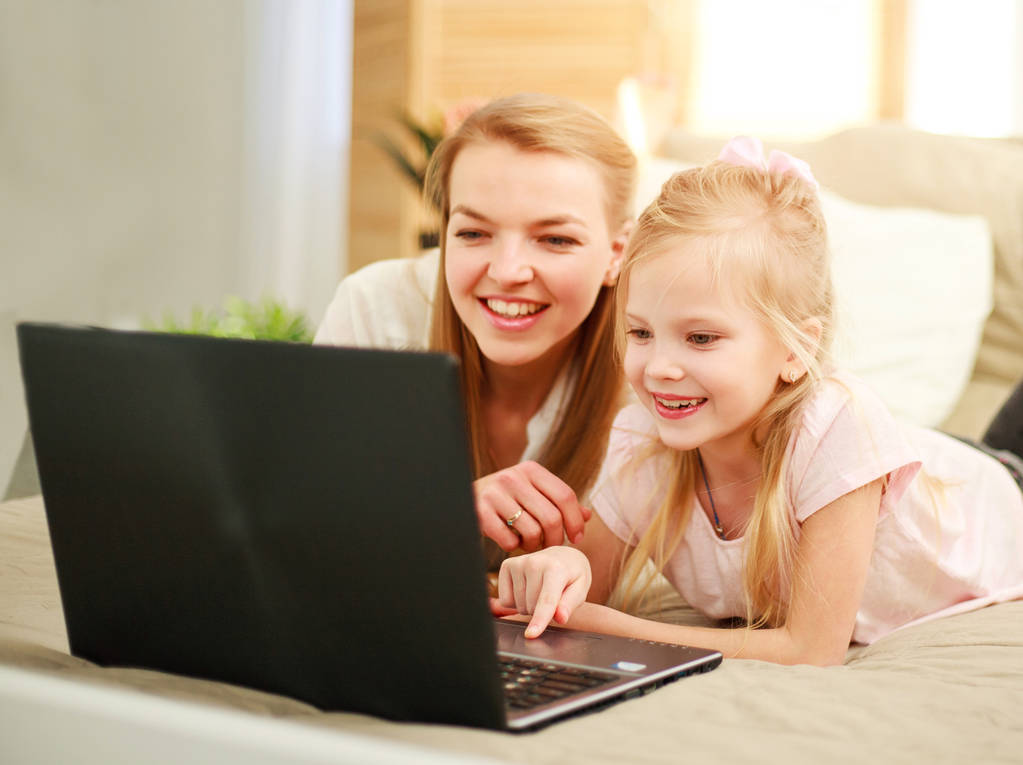 Felice madre di famiglia con figlia utilizzando computer portatile a casa
 - Foto, immagini