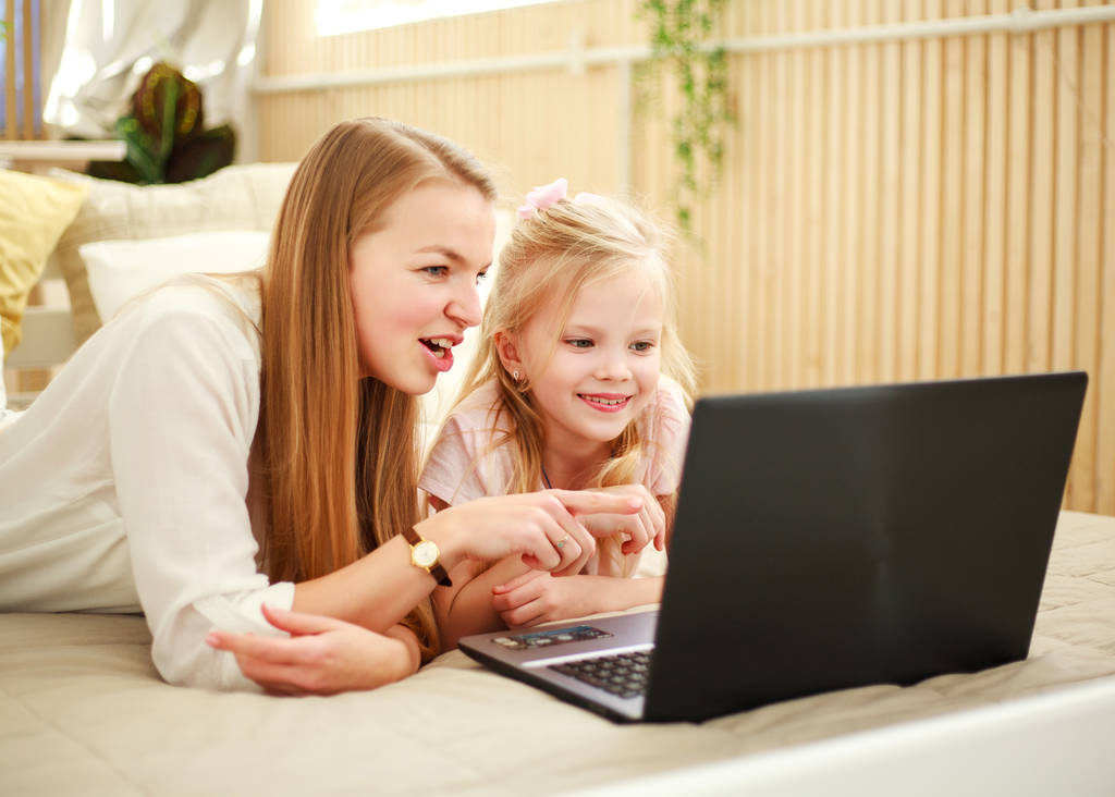 Happy family mother with daughter using computer laptop at home - Photo, Image