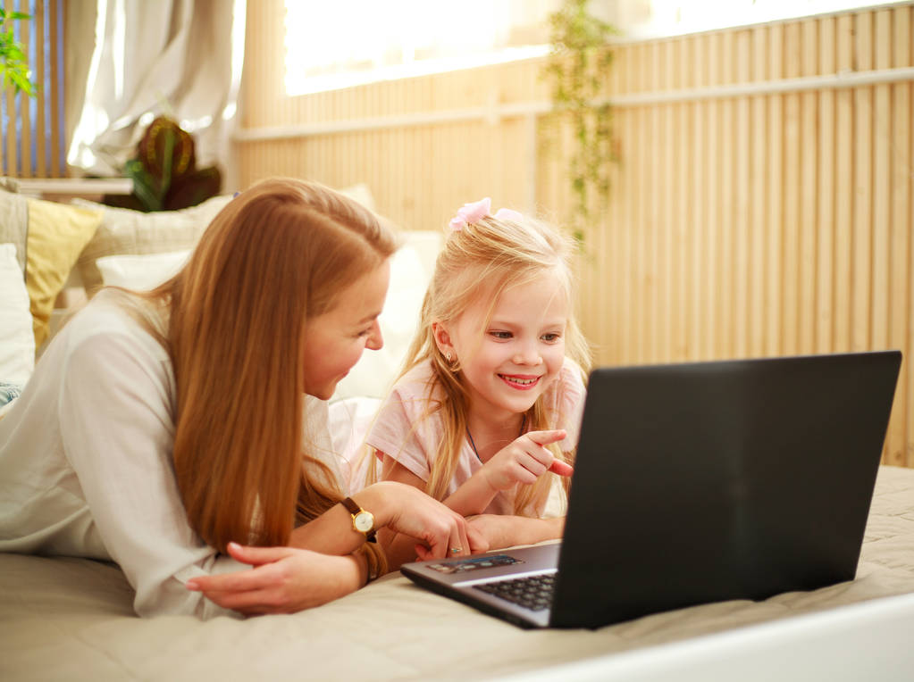 Mère de famille heureuse avec sa fille utilisant un ordinateur portable à la maison
 - Photo, image