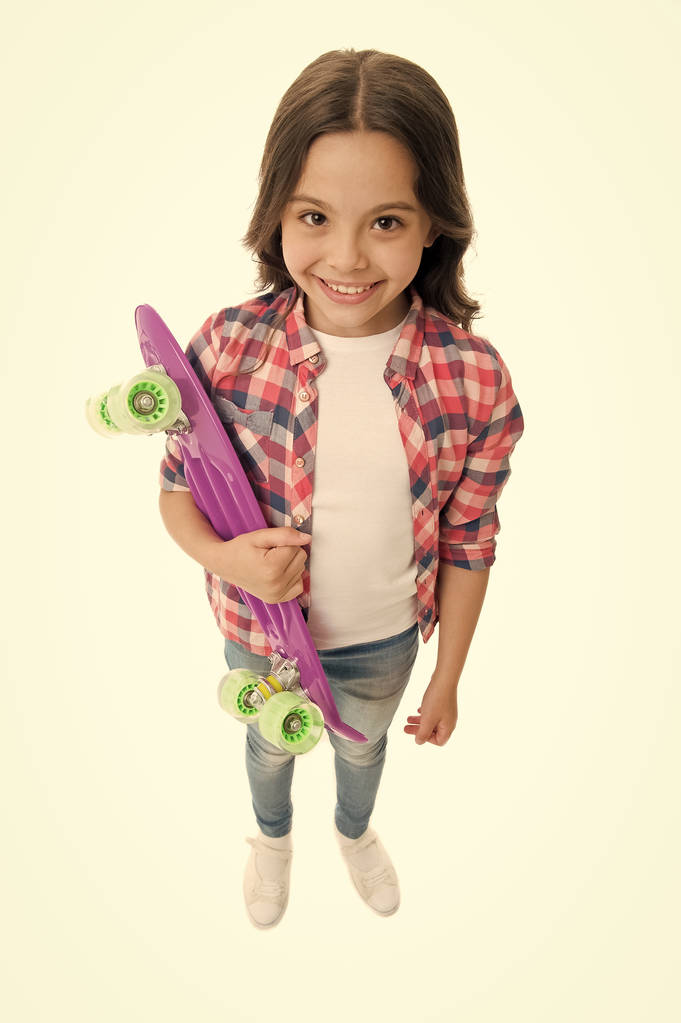 Fond of skateboarding. Kid girl happy carries penny board. Child likes skateboarding with penny board. Modern teen hobby. How to ride skateboard. Girl happy face carries penny board white background - Photo, Image