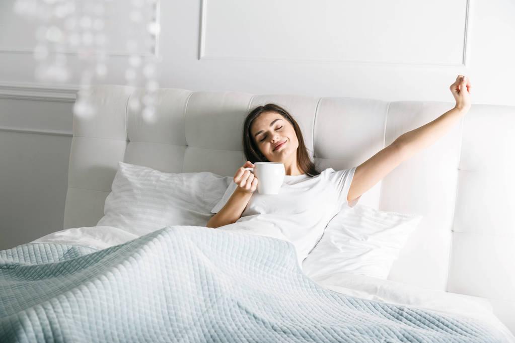 Mujer estirándose en la cama
 - Foto, imagen