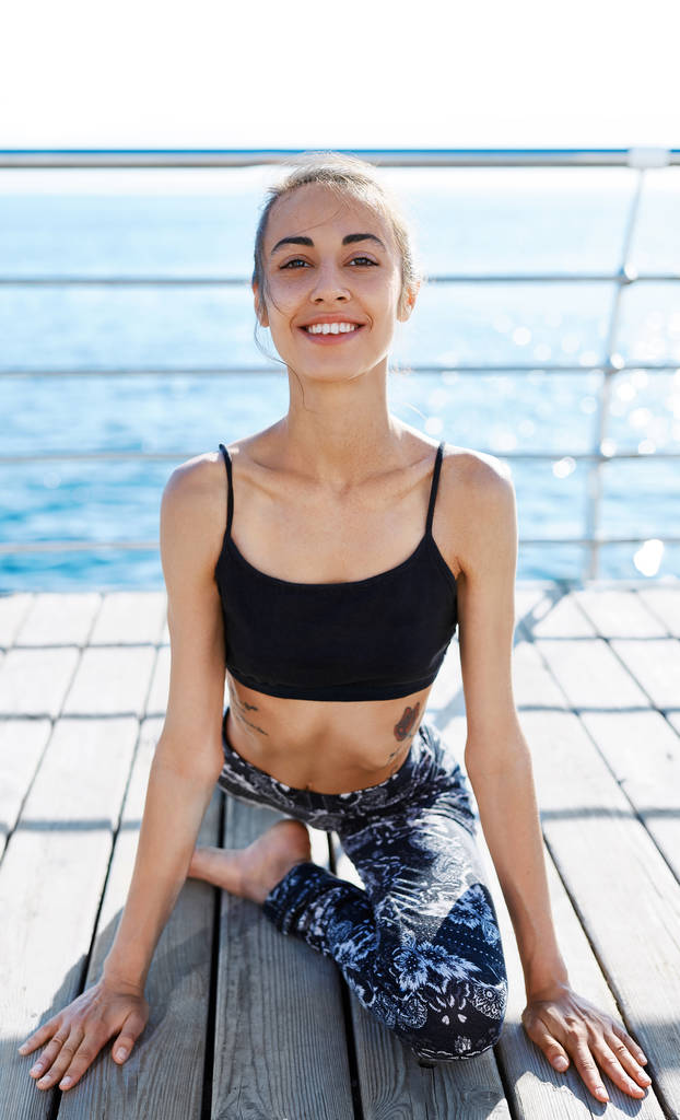 Sport fiatal nő portréja, hogy a jóga gyakorlatok és nyúlik a tengerparton. - Fotó, kép